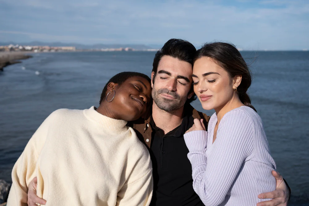 Three adults relaxing together by the sea