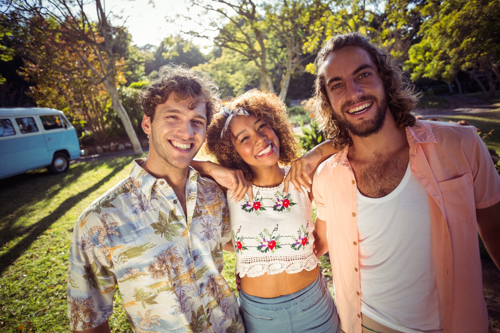Three friends smiling together in a park